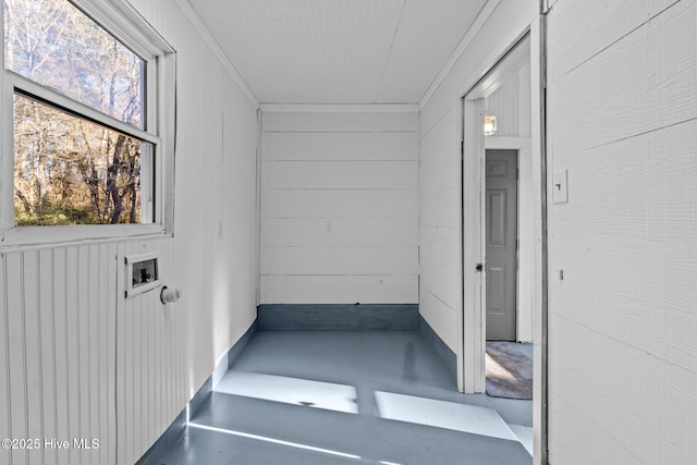 interior space featuring concrete floors, wooden walls, and crown molding