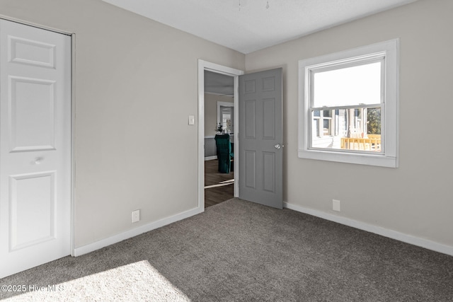 unfurnished bedroom with dark carpet