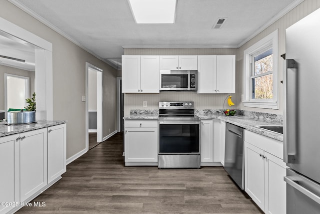 kitchen featuring white cabinets, appliances with stainless steel finishes, light stone countertops, and crown molding