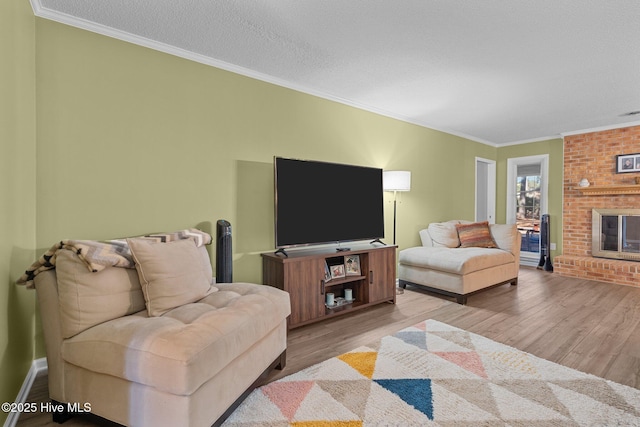 living room featuring a textured ceiling, light hardwood / wood-style flooring, ornamental molding, and a fireplace