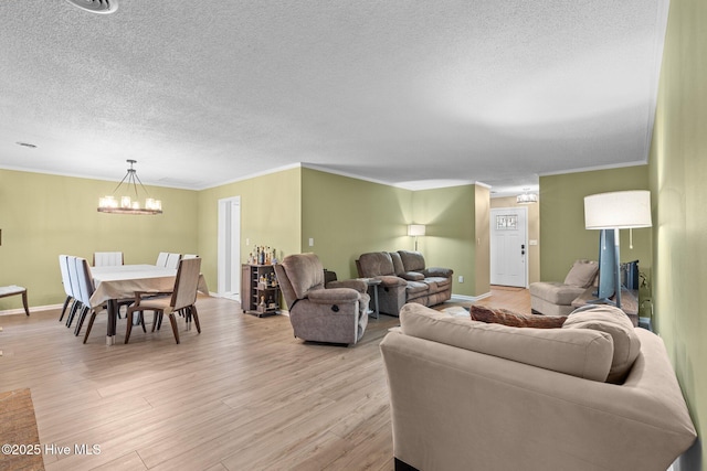 living room featuring light hardwood / wood-style flooring, crown molding, and an inviting chandelier