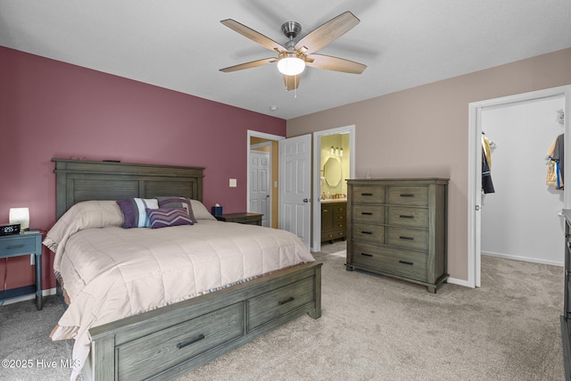 bedroom featuring ceiling fan, light carpet, and ensuite bath