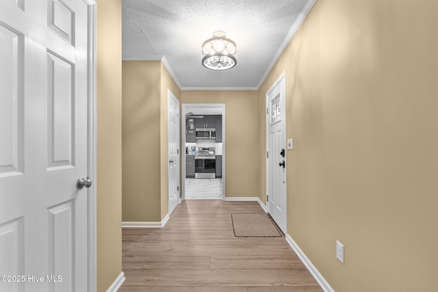 hallway with a textured ceiling, light hardwood / wood-style flooring, and ornamental molding