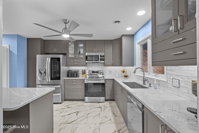 kitchen with light stone countertops, sink, stainless steel appliances, and tasteful backsplash