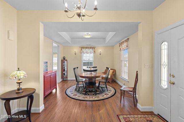 dining area featuring wood-type flooring, a chandelier, and a tray ceiling