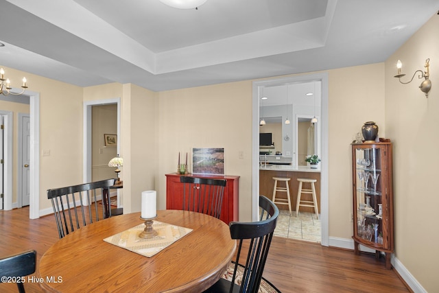 dining room featuring dark hardwood / wood-style flooring, a raised ceiling, and an inviting chandelier