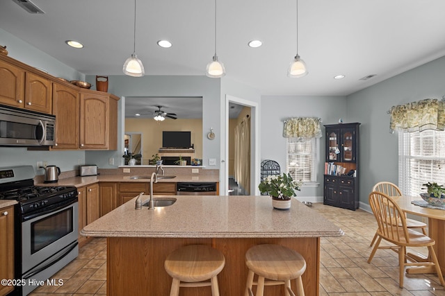 kitchen featuring kitchen peninsula, a kitchen island, appliances with stainless steel finishes, ceiling fan, and sink