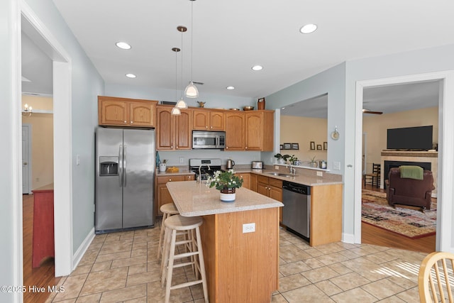 kitchen with sink, decorative light fixtures, a kitchen island, a breakfast bar, and appliances with stainless steel finishes