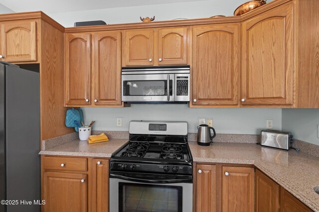 kitchen with appliances with stainless steel finishes and light stone counters