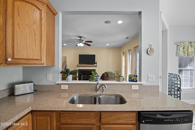 kitchen featuring light stone countertops, stainless steel dishwasher, ceiling fan, and sink