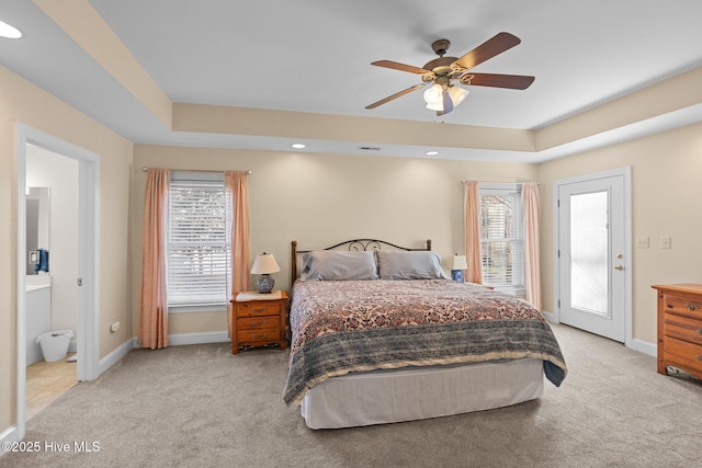 bedroom with ceiling fan, light colored carpet, multiple windows, and a tray ceiling