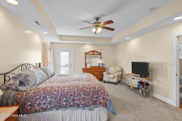 bedroom featuring ceiling fan, light carpet, and a tray ceiling