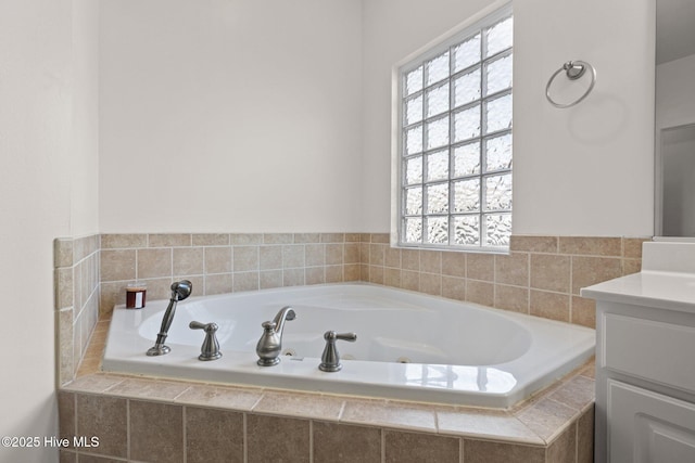 bathroom featuring tiled tub and vanity