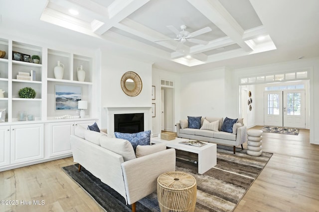 living room with beamed ceiling, light wood-type flooring, ceiling fan, coffered ceiling, and crown molding