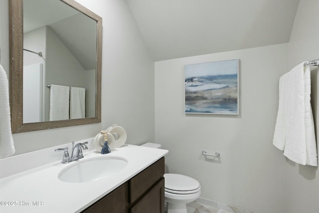 bathroom with toilet, vaulted ceiling, and vanity