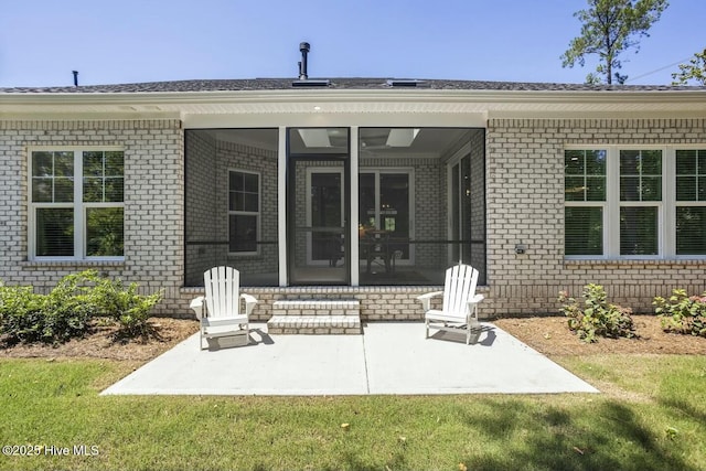 rear view of property with a yard, a sunroom, and a patio area