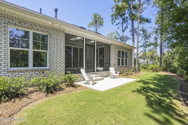 back of property featuring a yard, a sunroom, and a patio