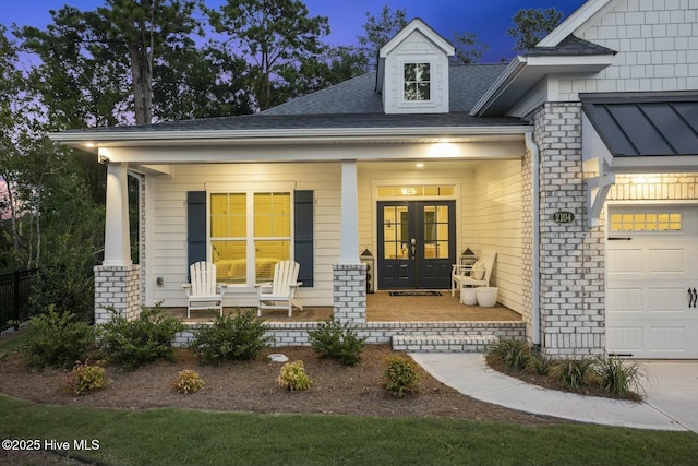 property entrance with french doors, covered porch, and a garage