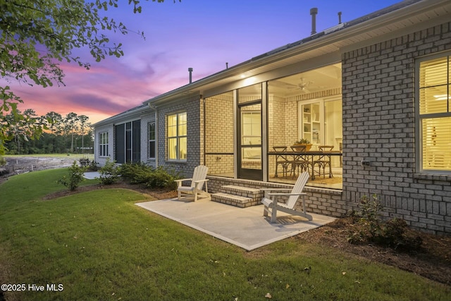 back house at dusk with a patio area, ceiling fan, and a yard