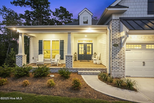 exterior entry at dusk with a porch, french doors, and a garage