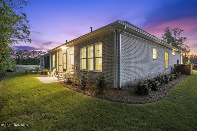 property exterior at dusk with a patio area, central AC unit, and a lawn