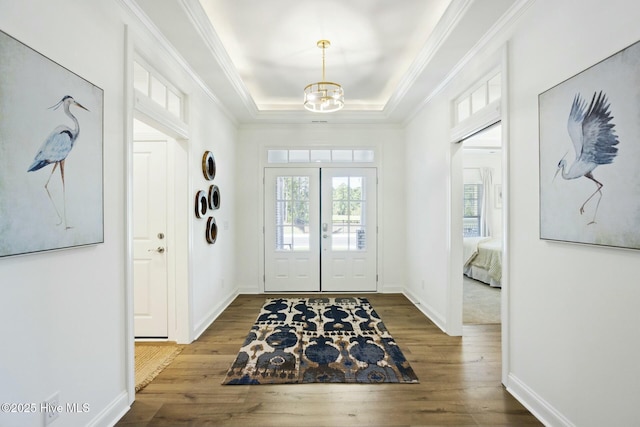 foyer featuring hardwood / wood-style flooring, french doors, an inviting chandelier, a tray ceiling, and ornamental molding