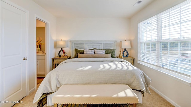 bedroom featuring ensuite bathroom and light carpet