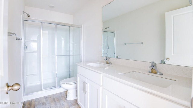 bathroom with toilet, wood-type flooring, an enclosed shower, and vanity