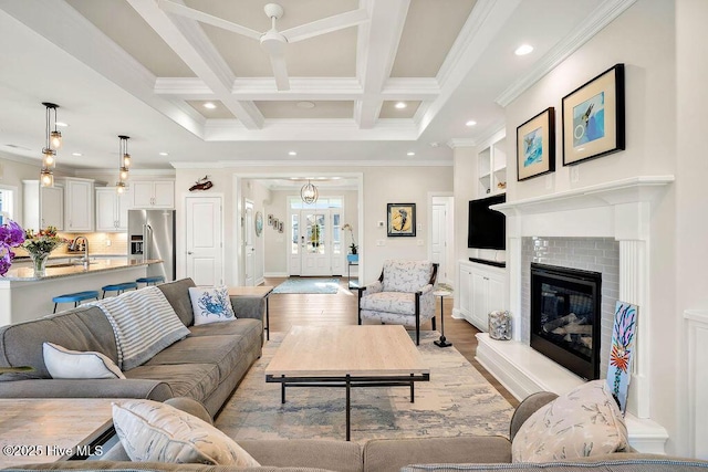 living room with light hardwood / wood-style floors, sink, ornamental molding, beam ceiling, and coffered ceiling