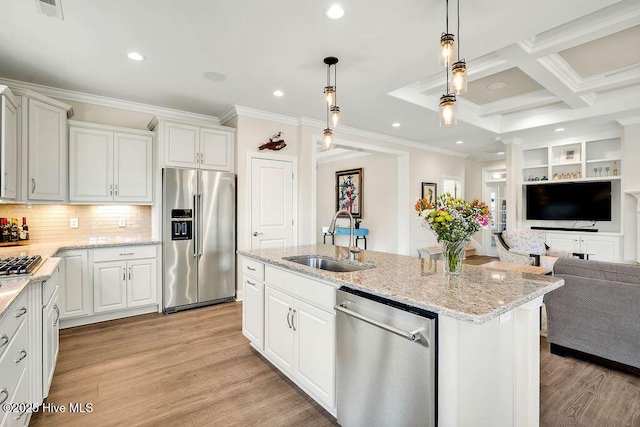 kitchen with appliances with stainless steel finishes, decorative backsplash, a kitchen island with sink, decorative light fixtures, and sink