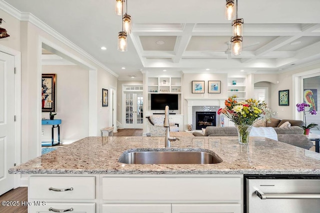 kitchen with built in shelves, light stone counters, white cabinetry, and pendant lighting