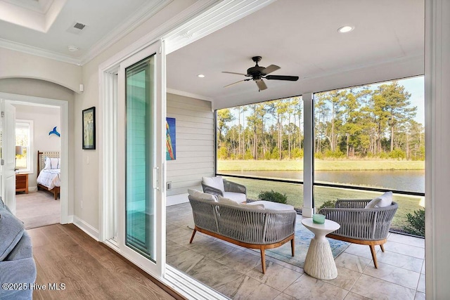 sunroom / solarium featuring ceiling fan and a water view