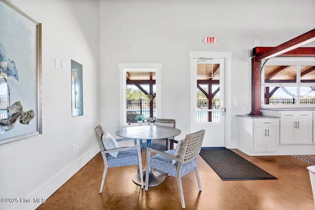 dining room featuring a high ceiling, electric panel, and concrete flooring