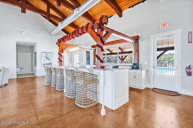 kitchen featuring concrete floors, white cabinetry, high vaulted ceiling, and beam ceiling