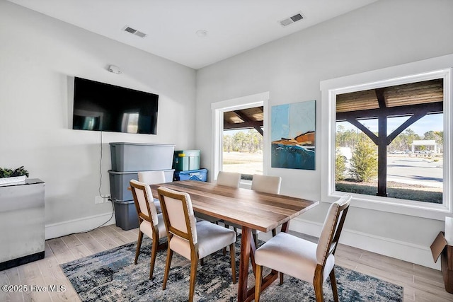 dining room with light hardwood / wood-style floors and a healthy amount of sunlight