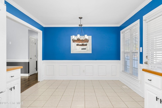 unfurnished dining area featuring an inviting chandelier, ornamental molding, and light tile patterned floors