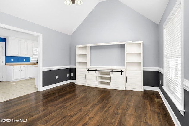 unfurnished living room with vaulted ceiling and dark hardwood / wood-style floors