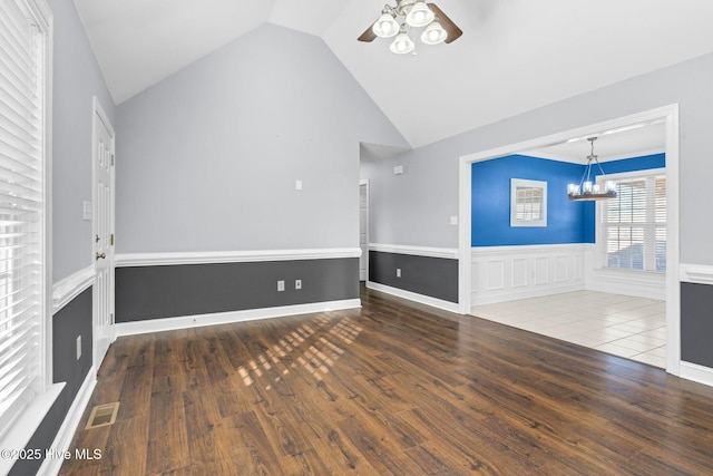 unfurnished living room featuring ceiling fan with notable chandelier, wood-type flooring, and vaulted ceiling