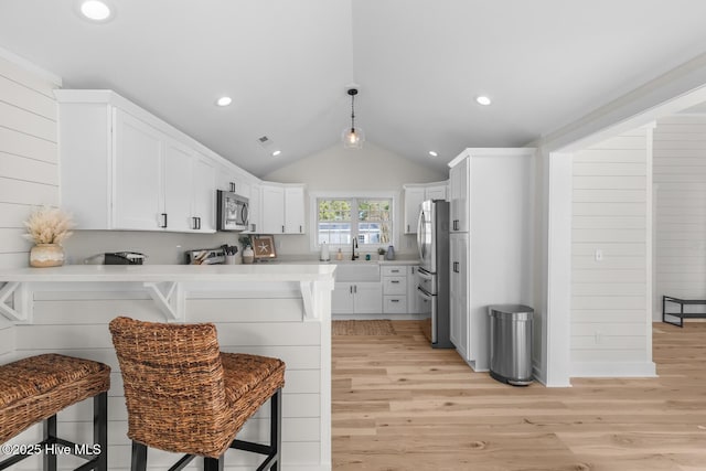 kitchen featuring white cabinetry, kitchen peninsula, appliances with stainless steel finishes, and a kitchen bar