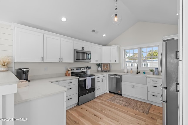 kitchen with stainless steel appliances, white cabinetry, sink, and decorative light fixtures