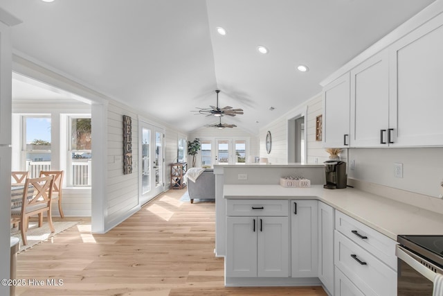 kitchen with white cabinetry, vaulted ceiling, light wood-type flooring, and kitchen peninsula