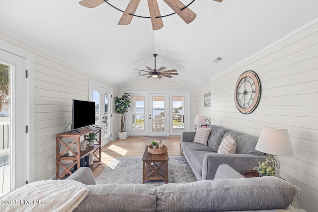 living room featuring lofted ceiling, a wealth of natural light, wooden walls, and wood-type flooring