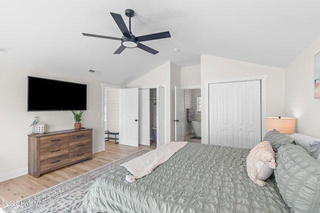 bedroom featuring ensuite bathroom, vaulted ceiling, light wood-type flooring, two closets, and ceiling fan