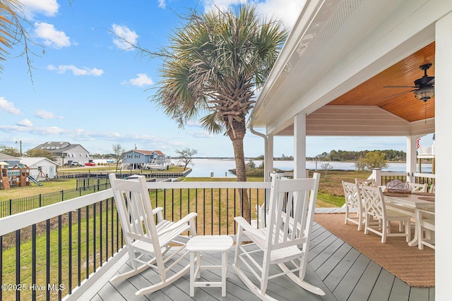 deck featuring a lawn, ceiling fan, and a water view