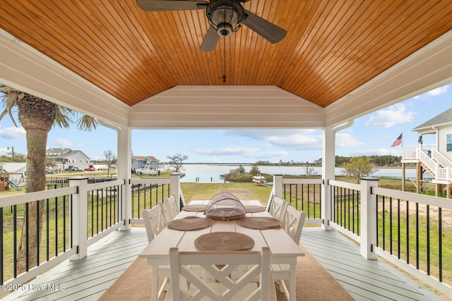 deck featuring a yard, a fire pit, ceiling fan, and a water view