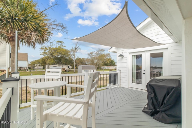 wooden deck featuring french doors, a storage shed, and a grill