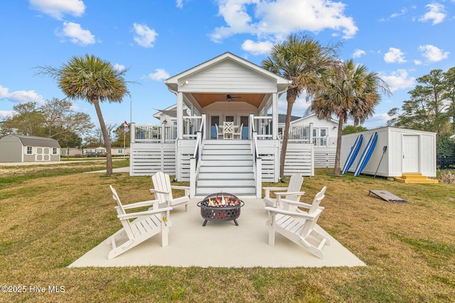 exterior space with ceiling fan, an outdoor fire pit, a deck, and a shed