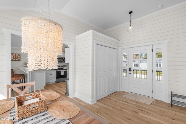 foyer featuring a notable chandelier, light hardwood / wood-style floors, and wood walls