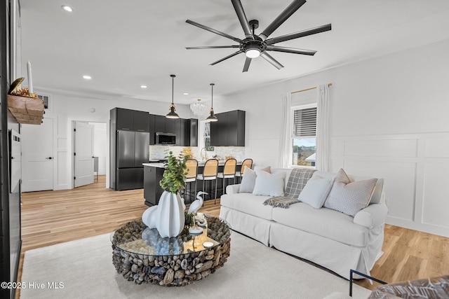 living room with ceiling fan, sink, and light wood-type flooring