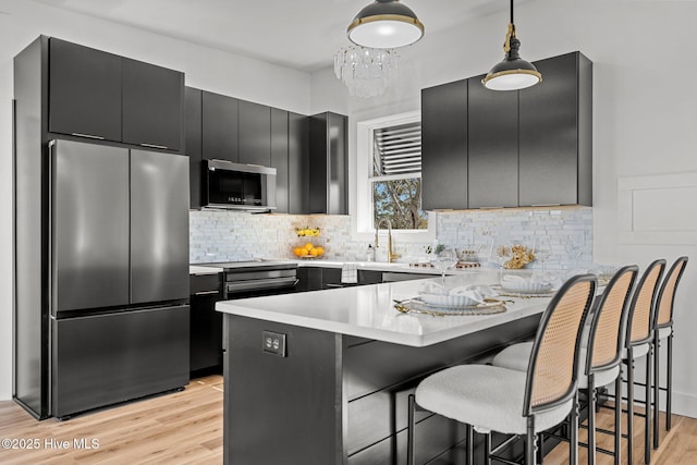 kitchen featuring stainless steel refrigerator, kitchen peninsula, hanging light fixtures, and light hardwood / wood-style flooring